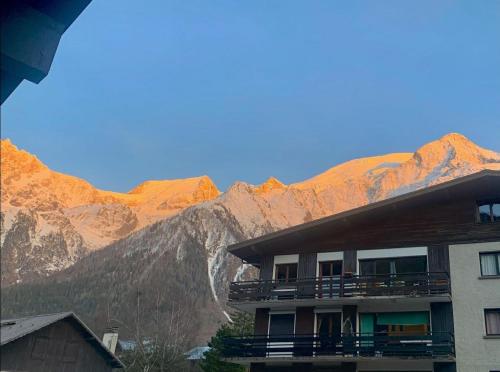 un bâtiment avec vue sur les montagnes en arrière-plan dans l'établissement Les Dryades - Rénové - Balcon avec vue Mt Blanc, aux Houches