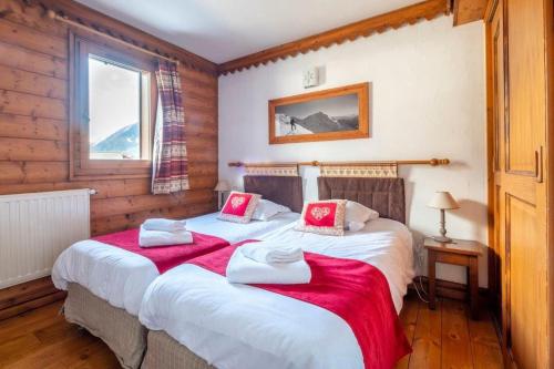 two twin beds in a room with wooden walls at Le Petit Paradis - Indoor pool and sauna in Chamonix-Mont-Blanc
