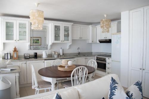a kitchen with white cabinets and a table and chairs at Palm Cove - 52 Chakas Cove, Penthouse-Literally on the Beach in Ballito