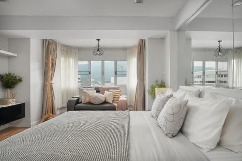 a white bedroom with a large bed and a couch at Cozy A at Nimman Studio Room in Condominium in Chiang Mai