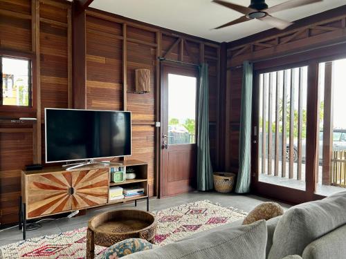 Il comprend un salon doté de murs en bois et d'une télévision à écran plat. dans l'établissement Kaz C2C - Une maison Balinaise avec jacuzzi, à Saint-Pierre