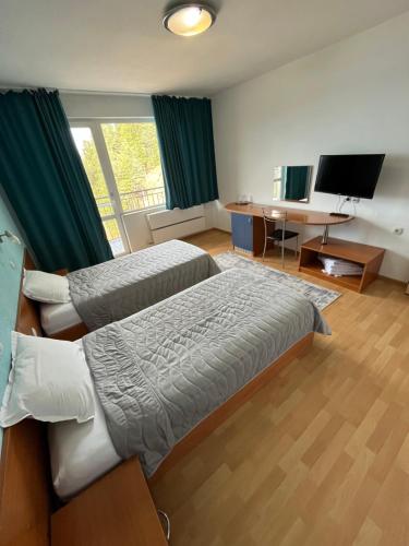 um quarto com 2 camas, uma secretária e uma televisão em Хотел ПАНОРАМА ДОСПАТ em Dospat
