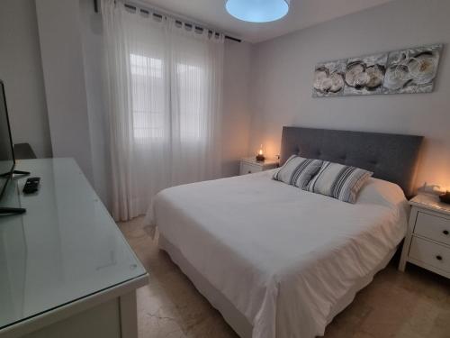 a white bedroom with a bed and a window at Apartamento Centro y Playa in Torremolinos