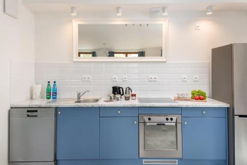 una cucina con armadi blu, lavandino e specchio di Rent like home - Puławska 221 a Varsavia