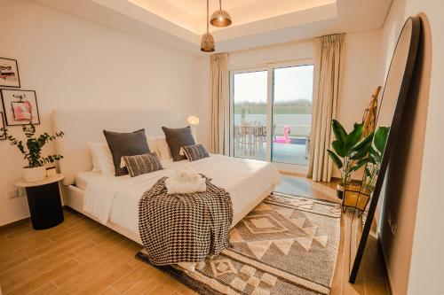 a bedroom with a bed and a large window at Private Pool & Beach At Your Doorstep in Abu Dhabi