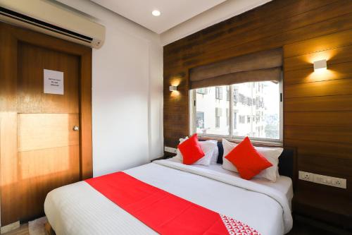 a bedroom with a bed with red and white pillows at Collection O Hotel Kyra in Ahmedabad