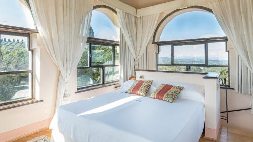 1 dormitorio con ventanas y 1 cama blanca con 2 almohadas en Villa Milani 14, Emma Villas, en Spoleto