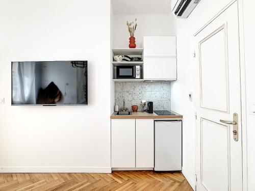 une cuisine avec des armoires blanches et un micro-ondes dans l'établissement Maison ÛMA - Wifi, Netflix, Mer et Centre, à Marseille