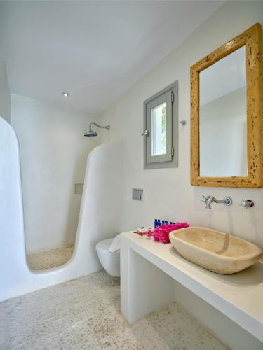a white bathroom with a sink and a mirror at Zefi Hotel & Suites in Naousa