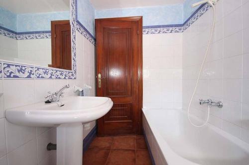 a bathroom with a sink and a toilet and a tub and a mirror at Casa Agrelo Ria de Noia in Argellas