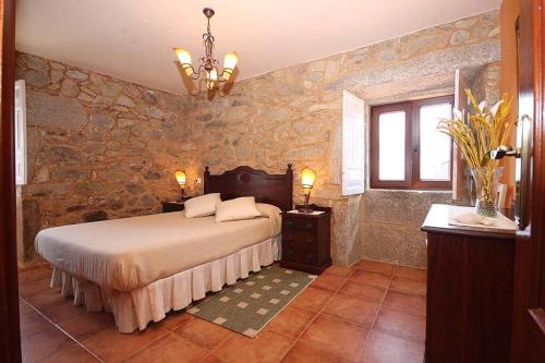 a bedroom with a bed and a stone wall at Casa Agrelo Ria de Noia in Argellas