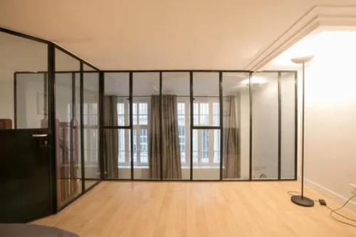 Cette grande chambre est dotée de murs en verre et de parquet. dans l'établissement Love in marais, à Paris
