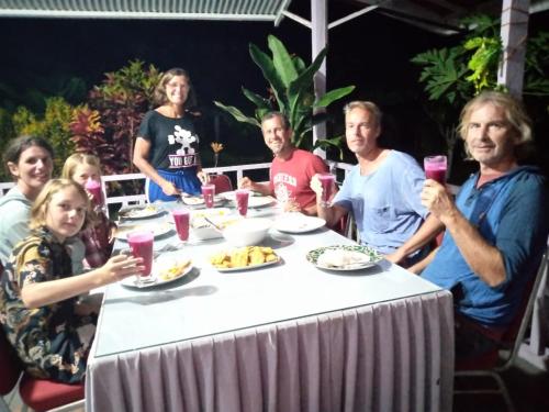 Pondok Oma for Solo Traveller في Lasikin: مجموعة من الناس يجلسون حول طاولة مع الطعام