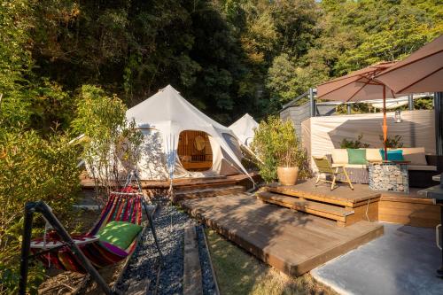 einen Hinterhof mit einem Zelt, einem Stuhl und einer Hängematte in der Unterkunft fabula glamping in Kimitsu