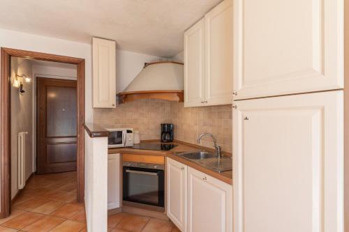 une cuisine avec des armoires blanches, un évier et un micro-ondes dans l'établissement DIFY René Payot - Chamonix-Mont-Blanc, à Chamonix-Mont-Blanc