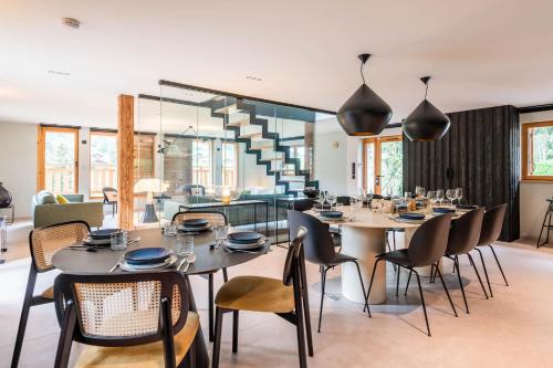 a dining room with tables and chairs and a staircase at SmartStay - Chalet Felix aux Confins in La Clusaz