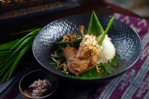 a black bowl of food with rice and meat at Rumah Luwih Bali in Keramas