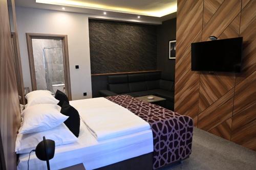 a bedroom with a bed and a flat screen tv at Hotel Zlatna Žita in Pale