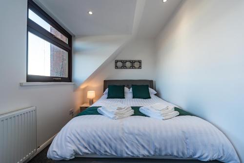 een slaapkamer met een bed met groene kussens en een raam bij Honey's Hideaway in Hull