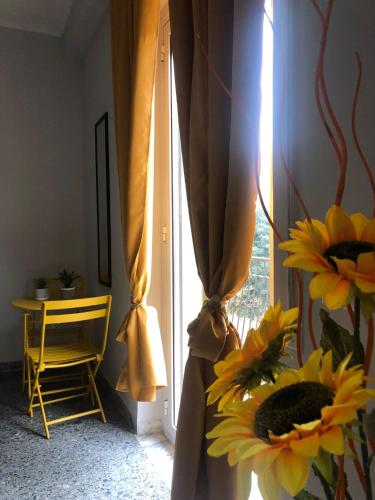 a window with a yellow curtain and flowers in a room at Flower Inn Marconi Roma in Rome