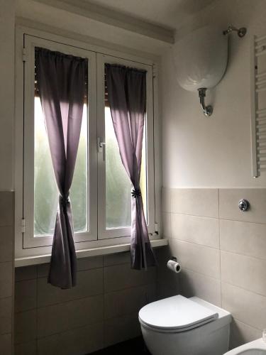 a bathroom with a toilet and a window with purple curtains at Flower Inn Marconi Roma in Rome