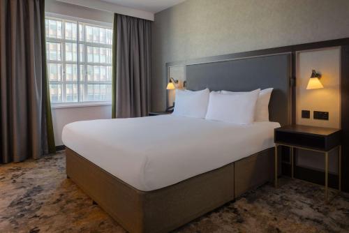a hotel room with a large bed and a window at Hilton Cardiff in Cardiff