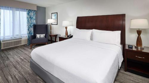 a hotel room with a large bed and a chair at Hilton Garden Inn Merrillville in Merrillville