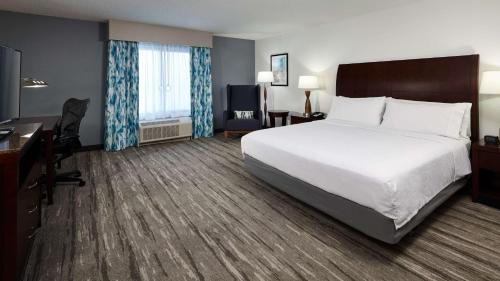 a hotel room with a large bed and a desk at Hilton Garden Inn Merrillville in Merrillville