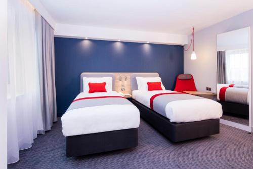 a hotel room with two beds with red pillows at Holiday Inn Express - Ringsheim by IHG in Ringsheim