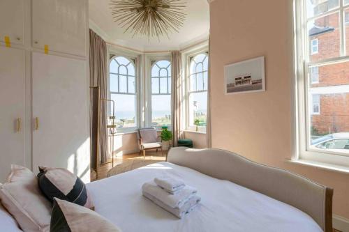 a bedroom with a bed with white sheets and windows at Bay View - Pet friendly in Margate