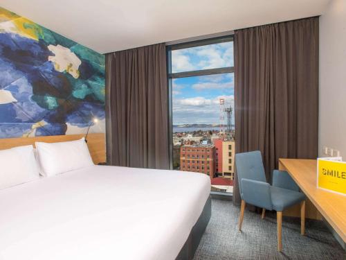 a hotel room with a bed and a large window at Ibis Styles Hobart in Hobart