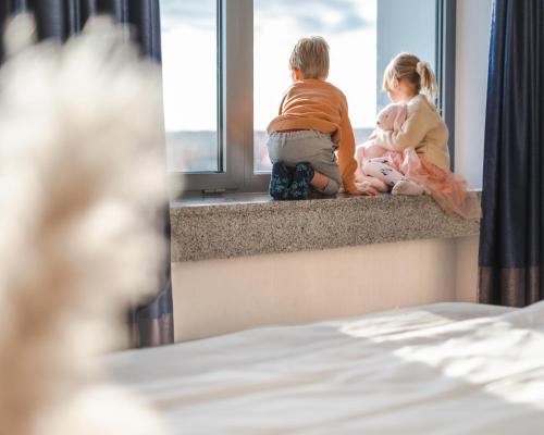 a little boy and girl sitting on a window sill looking out at Hotel Marina Club Old Town View in Gdańsk