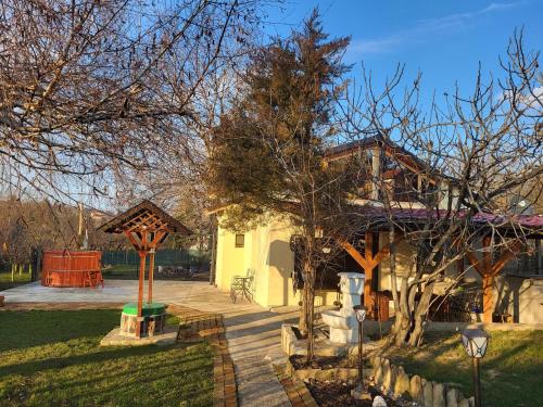 a yellow house with a tree in the yard at Vila Mila Fruška Gora in Velika Remeta