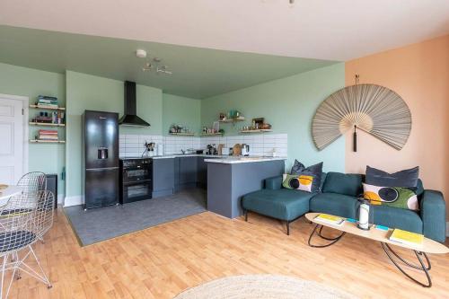 a living room with a blue couch and a kitchen at Canary, 2-bed seafront flat. Pet-friendly. in Margate