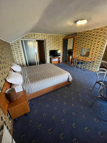 ドスパットにあるХотел ПАНОРАМА ДОСПАТの大きなベッドとデスクが備わるホテルルームです。