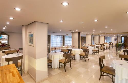 une salle à manger avec des tables et des chaises blanches dans l'établissement Ilisia Hotel Athens, à Athènes