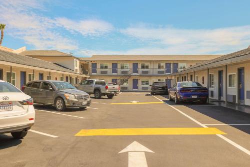 un estacionamiento con autos estacionados frente a un edificio en Motel 6 Tustin, CA Orange County en Tustin