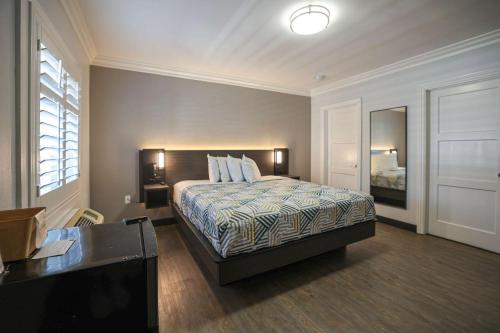 a bedroom with a bed and a desk and a mirror at Motel 6, Tustin, Orange County-CA in Tustin