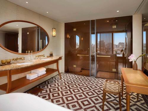 a bathroom with a shower and a sink and a mirror at Grand Mercure Hanoi in Hanoi