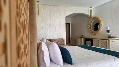 a bedroom with a large white bed with a mirror at Hôtel Jardins de lina et lea in Marrakesh