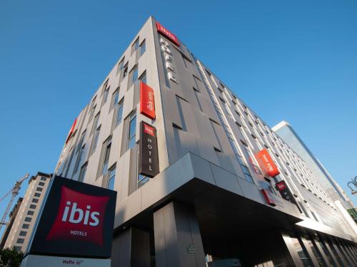a tall building with a sign in front of it at ibis Baku City in Baku