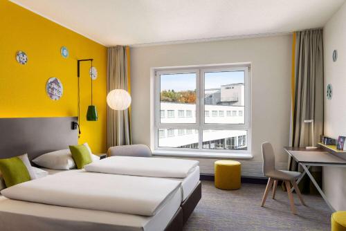 Pokój hotelowy z 2 łóżkami, biurkiem i oknem w obiekcie Vienna House Easy by Wyndham Coburg w mieście Coburg