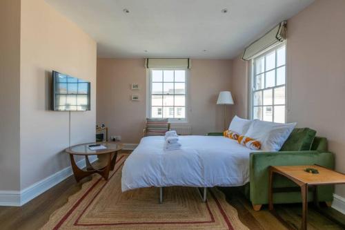 a bedroom with a bed and a green couch at Palm Heights - top floor luxury flat in Margate