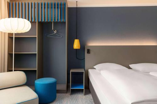 a hotel room with a bed and a chair at Vienna House Easy by Wyndham Neckarsulm in Neckarsulm