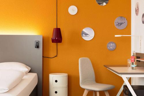 a bedroom with a bed and a table and a chair at Vienna House Easy by Wyndham Neckarsulm in Neckarsulm