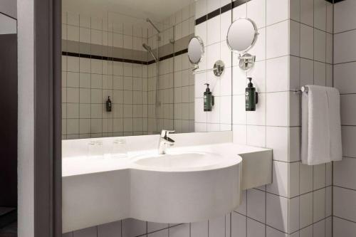 a white bathroom with a sink and a mirror at Vienna House Easy by Wyndham Neckarsulm in Neckarsulm