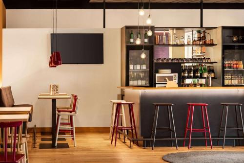 a bar in a restaurant with red stools at Vienna House Easy by Wyndham Neckarsulm in Neckarsulm