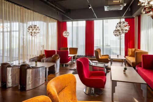 a waiting room with red chairs and tables at Amedia Express Graz Airport, Trademark Collection by Wyndham in Feldkirchen bei Graz