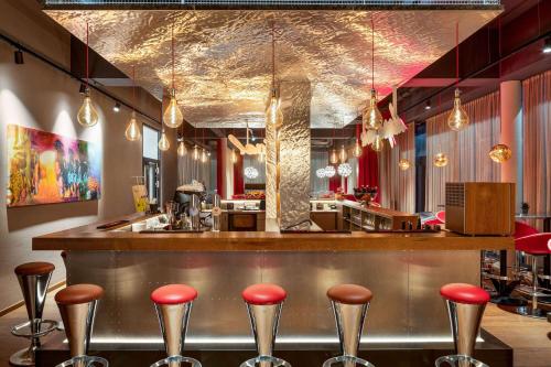 a bar in a restaurant with red stools at Amedia Express Graz Airport, Trademark Collection by Wyndham in Feldkirchen bei Graz