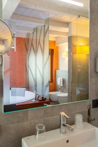 a bathroom with a mirror and a sink and a tub at Olimpia Hotel in Bormio